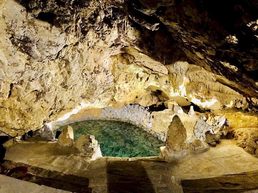 A jade-green lake embraces the cave, creating a mystical scene like a paradise on earth
